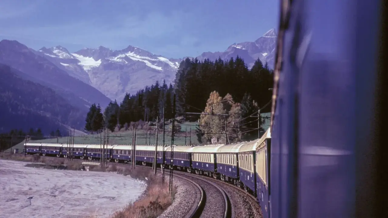 Der Istanbul Express fährt durch eine malerische Berglandschaft mit schneebedeckten Gipfeln und dichten Wäldern.