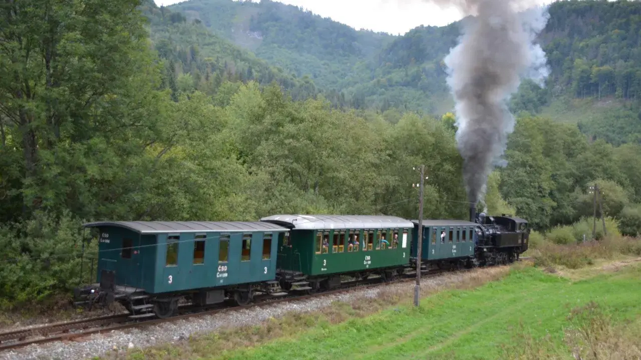 Dampflok der slowakischen Bahn fährt durch eine grüne Landschaft.