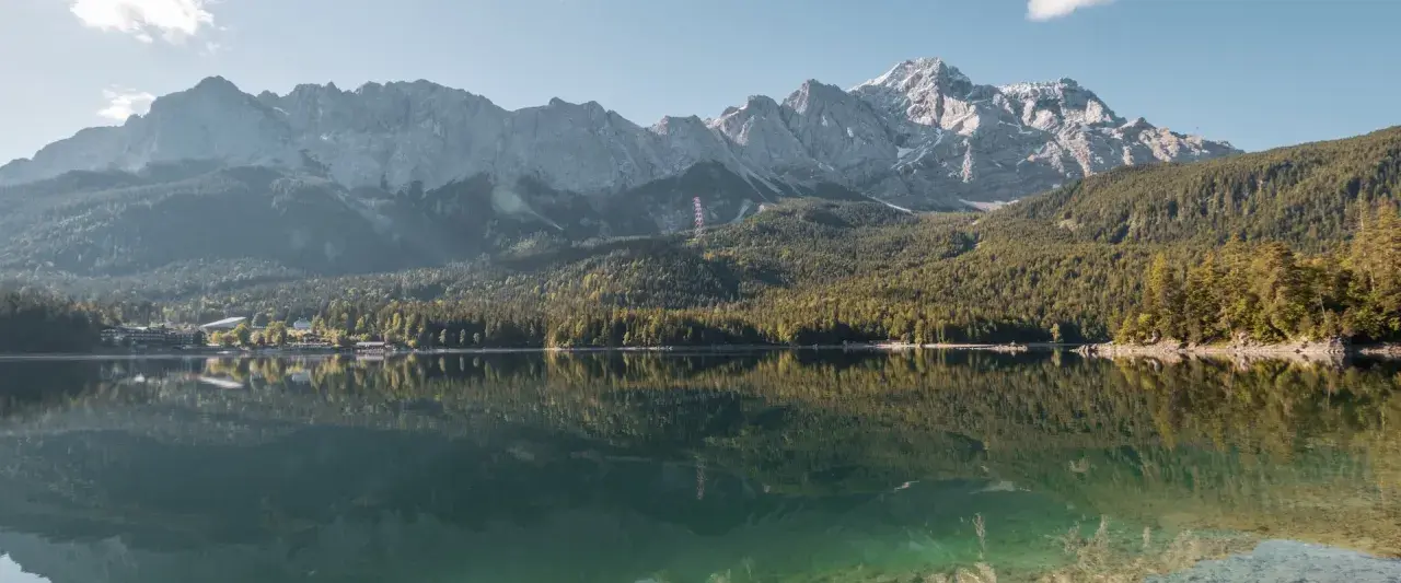 Spiegelglatter See vor bewaldeten Bergen. Ein Ort, der zum Camping am Staffelsee einlädt.