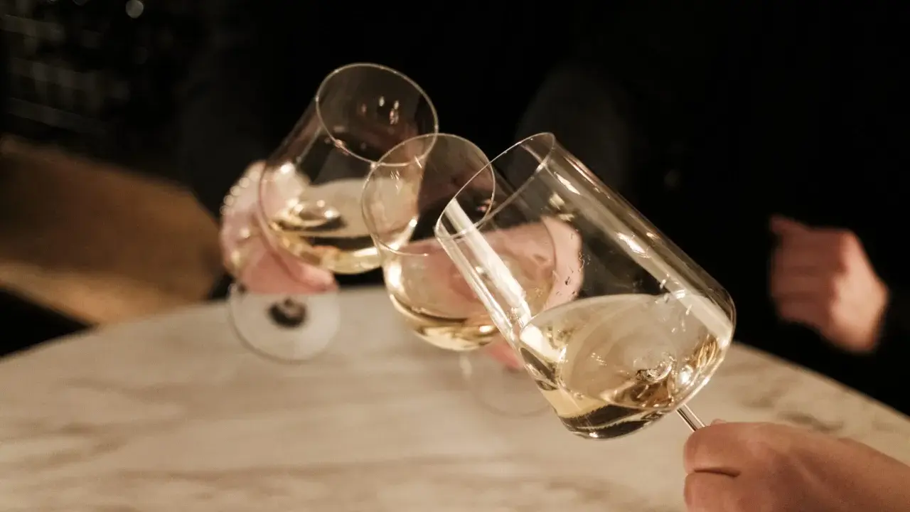 Drei Gläser Weißwein werden angestoßen. Ein schöner Moment nach einem langen Wein wandern.