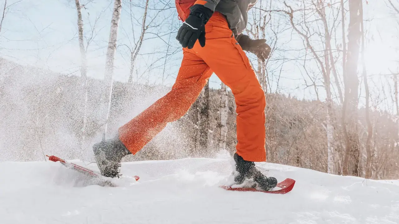 Person beim Schneeschuhwandern, die mit ihren speziellen Schuhen durch tiefen Schnee stapft.