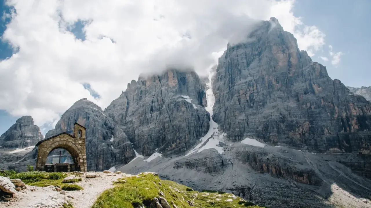 Kleine Kapelle vor imposanten Felsriesen in den Alpen. Ein perfekter Ort für mehrtageswanderungen in Europa.