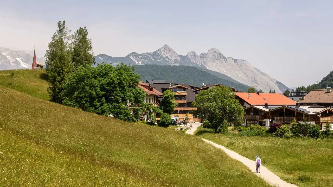 Ein Wanderweg führt durch blühende Wiesen zum malerischen Seefeld. Ein echter Geheimtipp mit Bergblick und traditioneller Architektur.