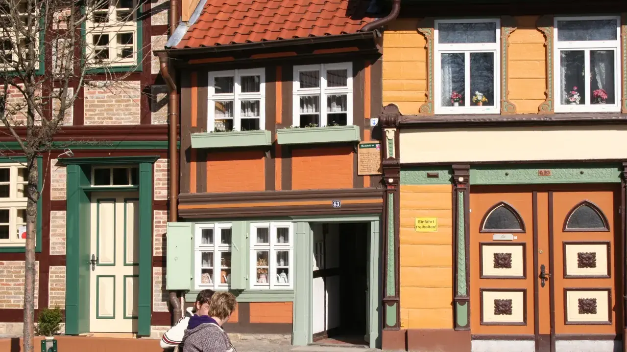 Fachwerkhäuser in Wernigerode, ein Ort voller geheimtipps. Zwei Personen sitzen auf einer Bank vor bunten Häusern.
