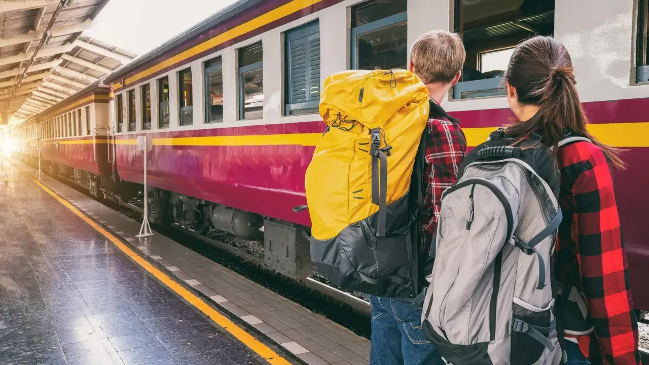 Zwei Rucksacktouristen warten am Bahnsteig auf ihren Zug. Mit ihrem world pass sind sie bereit für neue Abenteuer.