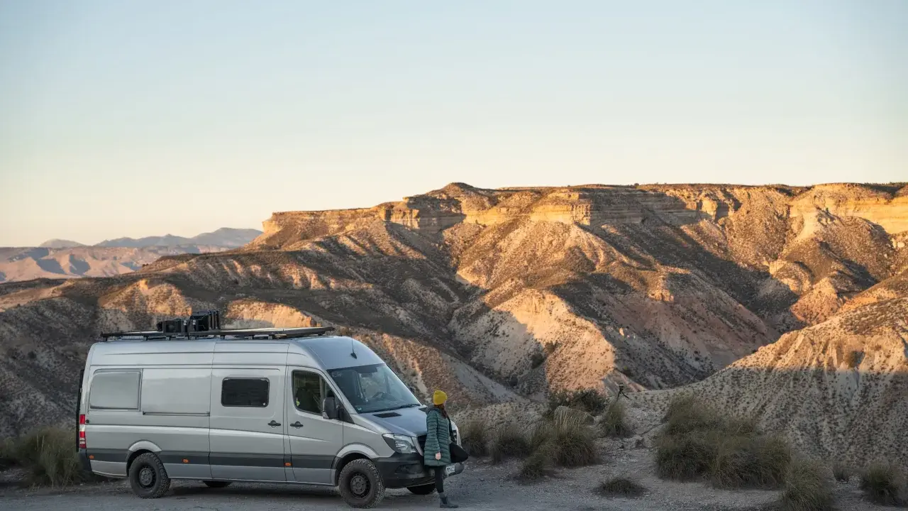 Ein Campervan steht in der Wüste Spaniens, bereit für wildcampen. Die Sonne beleuchtet die zerklüfteten Berge im Hintergrund.