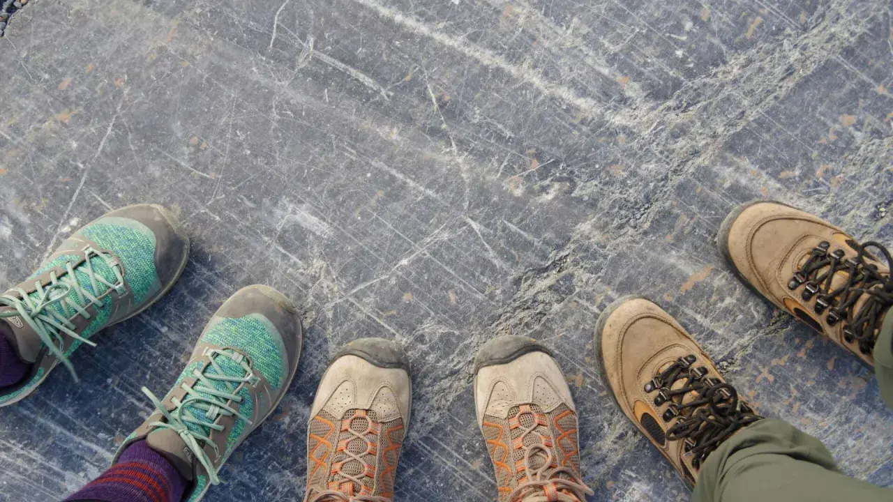 Vier Paar Wanderschuhe auf grauem Steinboden. Die Frage "wie fallen Meindl Schuhe aus?" bleibt offen, da keine Meindl-Schuhe zu sehen sind.