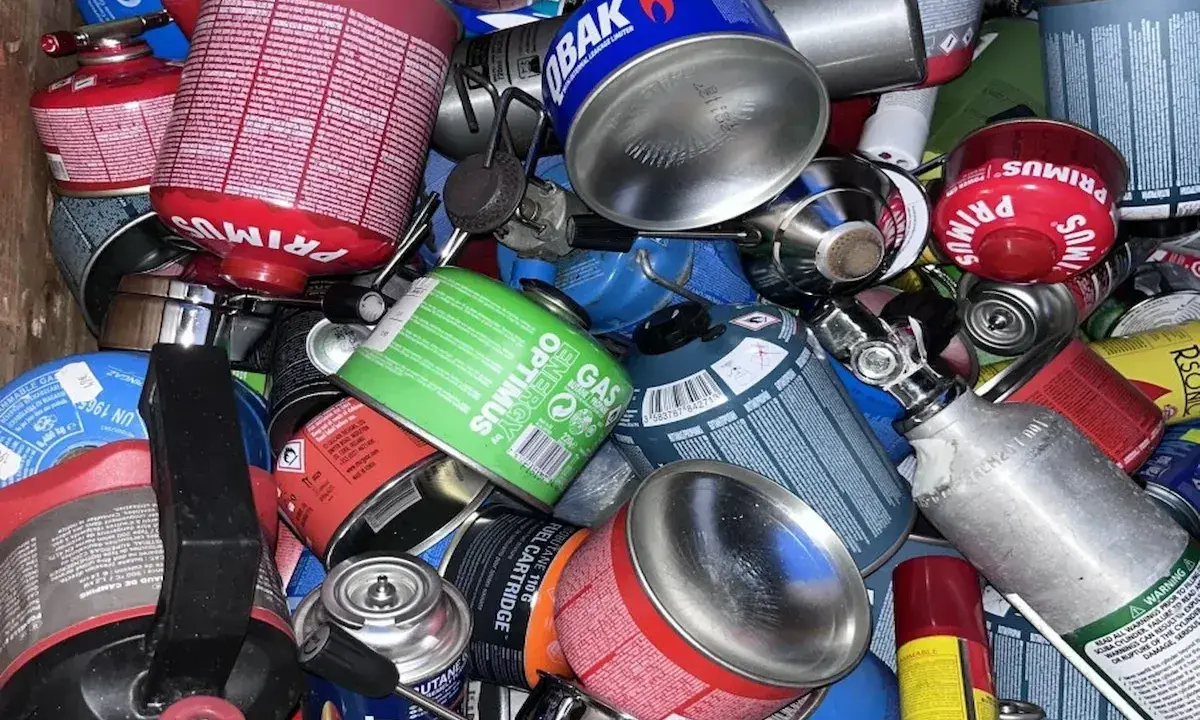 Ein Haufen verschiedener Gaskartuschen, darunter Primus und Optimus. Diese sind für Campingkocher gedacht, aber einige sehen aus, als wären sie für den Flugzeugtransport vorbereitet.