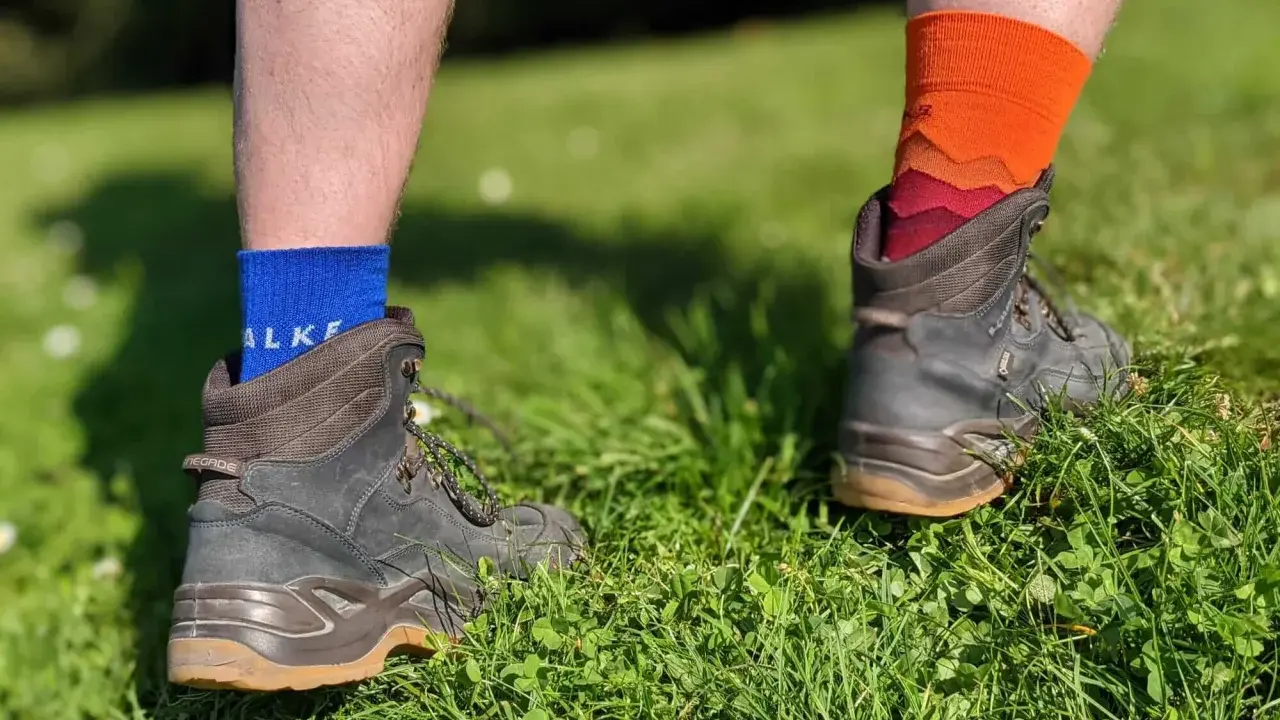 Falke TK1, TK2, TK3, TK4 Socken in Blau und Orange, getragen mit Wanderschuhen im Gras.
