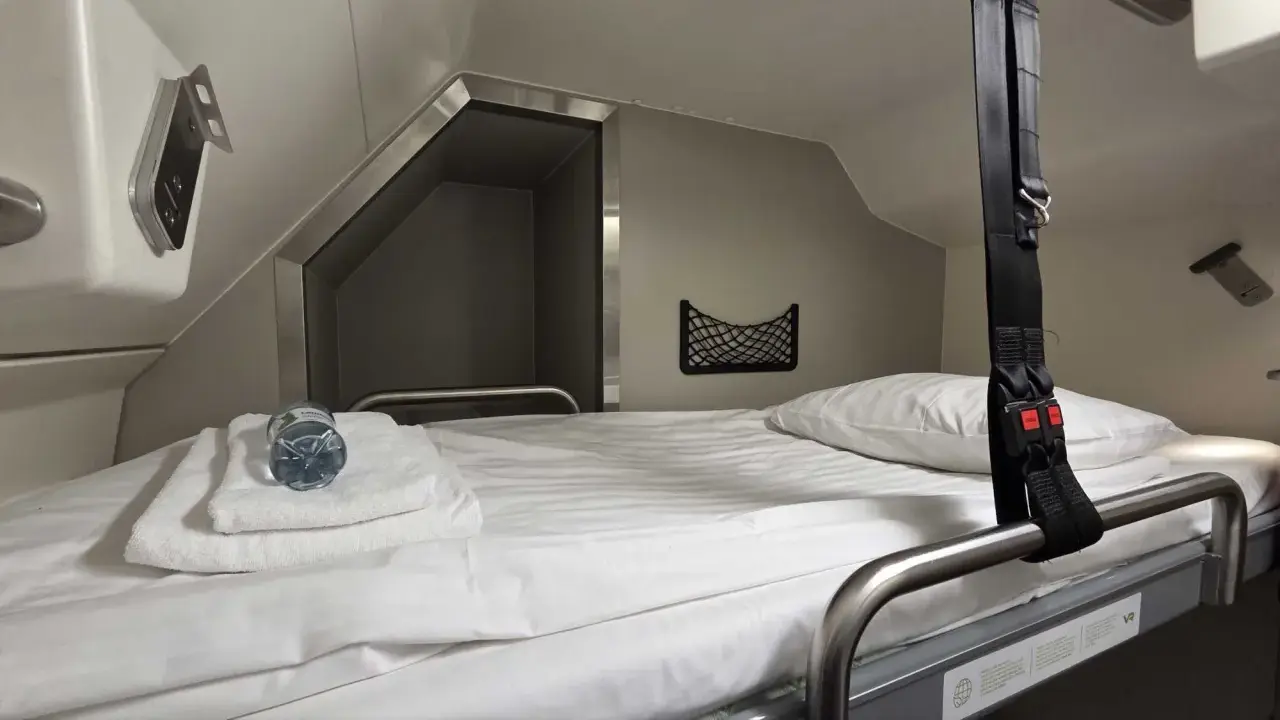 Gemütliches Bett im Schlafwagen, bereit für die Reise mit dem Santa Claus Express. Mit Handtüchern und Wasserflasche.