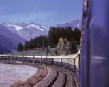 Der Istanbul Express fährt durch eine malerische Berglandschaft mit schneebedeckten Gipfeln und dichten Wäldern.
