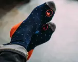 Blaue Socken mit orangen Akzenten und kleinen weißen Punkten. Die Socken haben ein rotes Logo und sind aus Merinowolle, ideal zum Waschen.