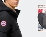 Schwarze Daunenjacke mit Logo, daneben ein Paket mit Flicken zur daunenjacke reparieren.