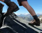 Wanderschuhe Kategorie B/C auf felsigem Untergrund, mit Blick auf schneebedeckte Berge.