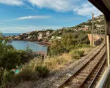 Blick aus dem Fenster eines Nachtzugs Paris Nizza auf eine Küstenlandschaft mit Häusern, Meer und Bahngleisen.
