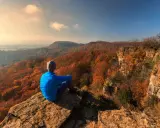 Ein Wanderer genießt den Ausblick auf die herbstliche Landschaft Norddeutschlands von einem Felsvorsprung.