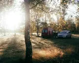 Sonnenaufgang im Herbst. Ein roter Camper und ein silberner Van stehen auf einer Wiese. Das ist Freiheit, das ist was ist wildcampen.