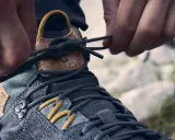 Hände schnüren Wanderschuhe für perfekten Halt. Die Schnürsenkel werden festgezogen, um die optimale Passform für das nächste Abenteuer zu gewährleisten.
