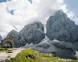 Kleine Kapelle vor imposanten Felsriesen in den Alpen. Ein perfekter Ort für mehrtageswanderungen in Europa.