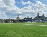 Grüne Wiese mit Blick auf die Elbe, die Brücke und die Frauenkirche. Ein Radfahrer genießt die Aussicht, um Dresden zu erleben.