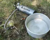 Soto Stormbreaker Kocher mit Brennstoffflasche und Topf auf Gras. Bereit für das nächste Abenteuer.