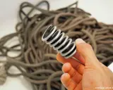 Ein Werkzeug mit Bürsten wird durch ein aufgewickeltes Kletterseil geführt. So wird das Kletterseil gewaschen.