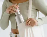 Frau verstaut ihre Edelstahlflasche in einer Stofftasche. So bleibt sie unterwegs sauber und bereit für die nächste Füllung.