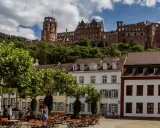 Heidelberg entdecken: Majestätisches Schloss thront über malerischen Häusern und grünen Bäumen. Ein idyllischer Platz lädt zum Verweilen ein.