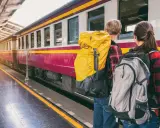 Zwei Rucksacktouristen warten am Bahnsteig auf ihren Zug. Mit ihrem world pass sind sie bereit für neue Abenteuer.