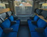 Leere Sitze im Nachtzug nach Stockholm. Blaue Polster mit orangefarbenen Punkten und schwarze Armlehnen laden zur Reise ein.