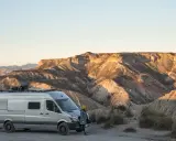 Ein Campervan steht in der Wüste Spaniens, bereit für wildcampen. Die Sonne beleuchtet die zerklüfteten Berge im Hintergrund.