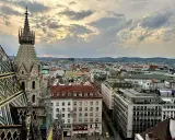 Blick über die Dächer Wiens bei Sonnenuntergang. Ein Turm des Stephansdoms ragt empor. Ein perfekter Moment, um Wien zu erleben.