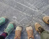 Vier Paar Wanderschuhe auf grauem Steinboden. Die Frage "wie fallen Meindl Schuhe aus?" bleibt offen, da keine Meindl-Schuhe zu sehen sind.