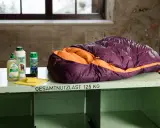 Lila-orangefarbener Exped-Schlafsack bereit zum Schlafsack waschen, daneben Reinigungsmittel und Schwamm.