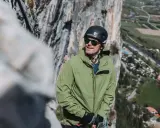 Bergsteiger in grüner, wasserdichter Jacke und Helm blickt in die Ferne. Die Ausrüstung zeigt, was wasserdicht bedeutet: Schutz bei jedem Wetter.