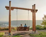 Zwei Personen auf einer Schaukel mit Blick auf eine Stadt am Fluss. Ein idyllischer Ort für Ausflugsziele Rheinland-Pfalz.