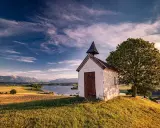 Kleine Kapelle auf einem Hügel mit Blick auf einen See und Berge. Ein **Geheimtipp Urlaub November Deutschland** für ruhige Tage.