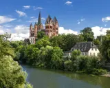 Ein malerischer Blick auf den Limburger Dom, umgeben von üppigem Grün und dem Fluss Lahn. Perfekt für einen Urlaub in Hessen.