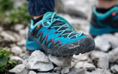 Blaue Salewa Wanderschuhe mit türkisen Schnürsenkeln, bereit für jedes Abenteuer auf steinigem Untergrund.