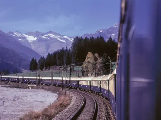 Der Istanbul Express fährt durch eine malerische Berglandschaft mit schneebedeckten Gipfeln und dichten Wäldern.