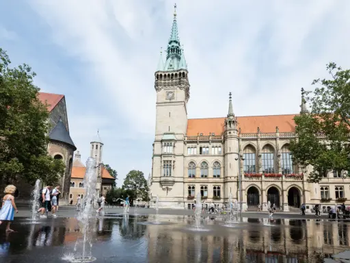 Kinder planschen im Brunnen vor dem Rathaus. Hier kann man in Braunschweig viel erleben, z.B. den Dom besichtigen.