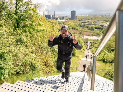 Glücklicher Mann erklimmt Treppen, genießt die Aussicht und verbrennt dabei Kalorien beim Wandern.