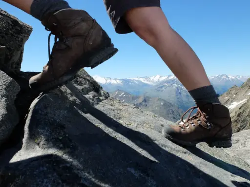 Wanderschuhe Kategorie B/C auf felsigem Untergrund, mit Blick auf schneebedeckte Berge.