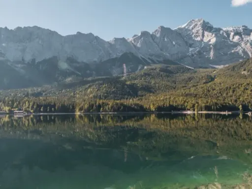 Spiegelglatter See vor bewaldeten Bergen. Ein Ort, der zum Camping am Staffelsee einlädt.
