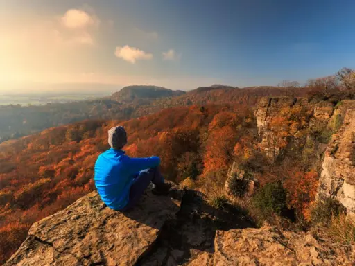 Ein Wanderer genießt den Ausblick auf die herbstliche Landschaft Norddeutschlands von einem Felsvorsprung.