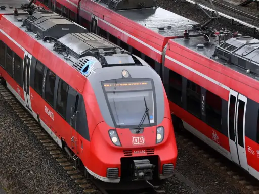 Zwei rote Regio-Züge der Deutschen Bahn stehen nebeneinander auf den Gleisen.