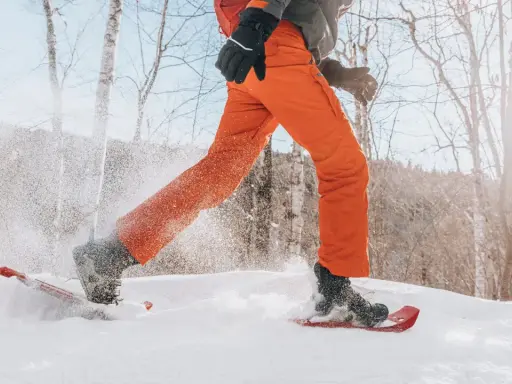 Person beim Schneeschuhwandern, die mit ihren speziellen Schuhen durch tiefen Schnee stapft.