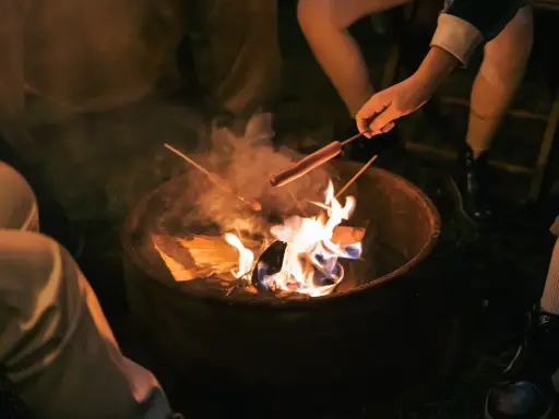 Kinder machen Feuer und rösten Würstchen über der Flamme.