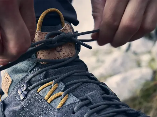 Hände schnüren Wanderschuhe für perfekten Halt. Die Schnürsenkel werden festgezogen, um die optimale Passform für das nächste Abenteuer zu gewährleisten.