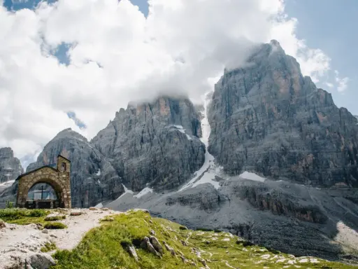 Kleine Kapelle vor imposanten Felsriesen in den Alpen. Ein perfekter Ort für mehrtageswanderungen in Europa.